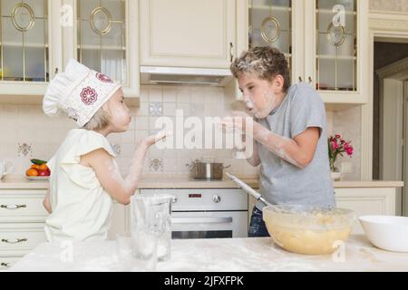 Frère et soeur ont du plaisir à jouer avec la farine dans la cuisine. Banque D'Images