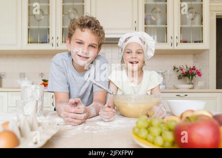 Portrait d'enfants gaies tachés de farine dans la cuisine. Banque D'Images