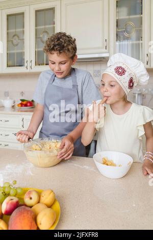 Les enfants ont plaisir à cuisiner de la tarte aux pommes dans la cuisine. Banque D'Images