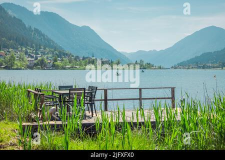 Belles rives du lac de weissensee en Autriche, magnifique toile de fond avec lac alpin dans la chaleur de l'été. Chaises longues et table vues à l'avant Banque D'Images