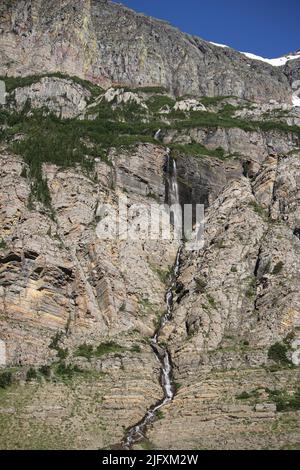 Chute d'eau immaculée, falaises rocheuses colorées, pins verts, Piegan & Siyeh Pass Trailhead, en direction de Sun Road, Glacier National Park, Montana, États-Unis Banque D'Images