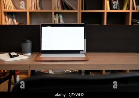 Ordinateur portable écran blanc maquette sur une table en bois dans un espace de travail ou une bibliothèque. Banque D'Images