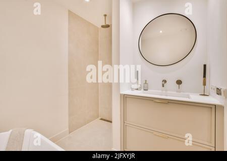 Lavabo avec miroir et baignoire propre située près de la boîte à douche dans la salle de bains moderne avec des murs carrelés de blanc Banque D'Images