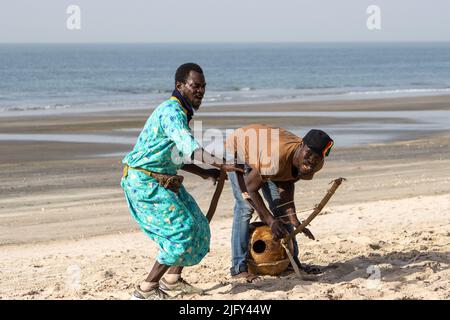 KOTU, SERREKUNDA, GAMBIE - 3 FÉVRIER 2022 musiciens traditionnels sur la plage de Kotu avec un shaker Kora et Flame Tree (Delonix regia) avec la mer Banque D'Images