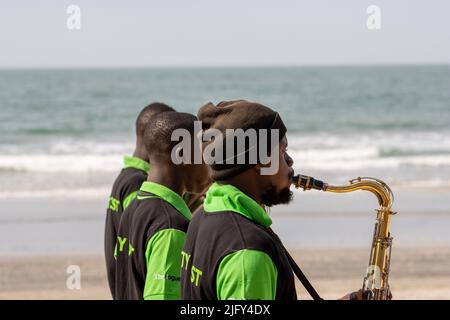 KOTU, SERREKUNDA, GAMBIE - 29 JANVIER 2022 la Gambie National Scout Band jouant sur la plage de Kotu - saxophoniste avec la mer en arrière-plan Banque D'Images