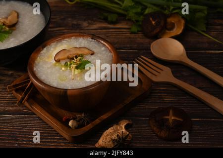 Porridge de riz, bouillie de riz ou congee avec champignons shiitake, tranche de gingembre et de scallion servis dans un bol en bois pour un repas léger Banque D'Images