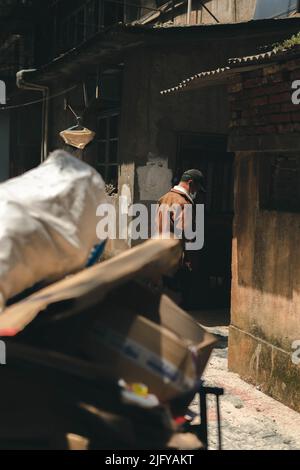 Photo verticale sélective d'un homme se tenant entre deux anciens bâtiments Banque D'Images