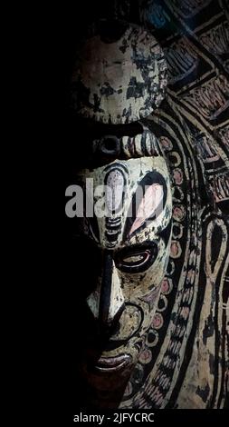 Un masque africain en bois, magnifiquement sculpté et peint sur un fond noir spectaculaire. Banque D'Images