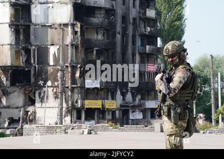 Un membre de l'armée ukrainienne se trouve devant des bâtiments endommagés dans la région de Borodyanka à Kiev, alors que Taoiseach Micheal Martin se rend en Ukraine pour réitérer la solidarité irlandaise avec les autorités ukrainiennes face à l'invasion russe. Date de la photo: Mercredi 6 juillet 2022. Banque D'Images