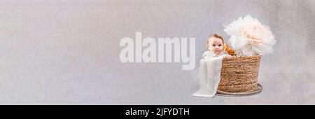 Bébé dans un panier sur fond gris. Photo isolée avec lumière studio. Se préparer à l'accouchement, à une enfance heureuse et à passer du temps avec les enfants. Banque D'Images