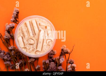 Vue de dessus du thé au lait avec de la glace dans du verre en plastique sur fond orange Banque D'Images
