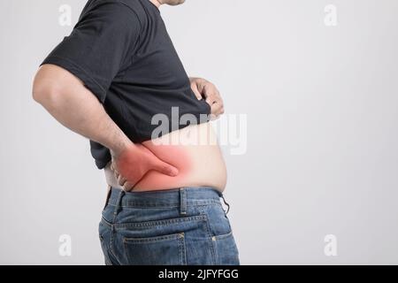 Douleur du corps, douleur de la hanche ou effet du foie problème : gras homme utilisant sa main et appuyant sur la position de la hanche. Studio tourné sur fond gris. Banque D'Images