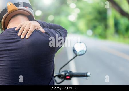 Motocycliste avec douleur ou concept fatigué : Homme rider se touchant sur son cou ou son épaule et se sentant fatigué après une longue moto. Prise de vue en extérieur activée Banque D'Images