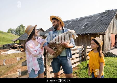 bonne femme regardant le mari debout avec de l'agneau à la ferme de bétail Banque D'Images