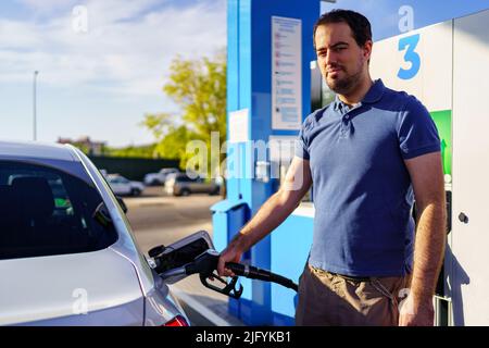 Homme adulte remplissant le réservoir d'essence d'une voiture à la station-service. Banque D'Images