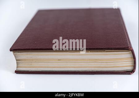Le grand livre rouge sur fond neutre. Livre fermé avec pages jaunrées. Encyclopédie de couverture rigide. Gros plan. Mise au point sélective. Banque D'Images