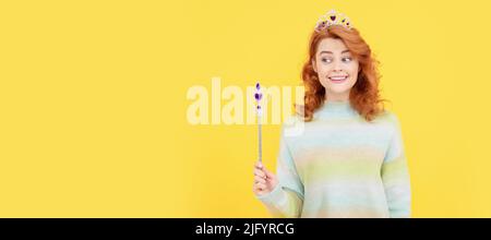 bonne femme à tête rouge dans la couronne de reine avec baguette magique, magie. Femme isolée visage portrait, bannière avec espace de copie. Banque D'Images