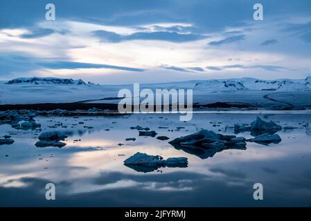 Scène tranquille au glacier de Jökulsárlón au cours de l'heure bleue, ciel spectaculaire reflété dans l'eau, Breiðamerkurjökull en arrière-plan, Islande Banque D'Images