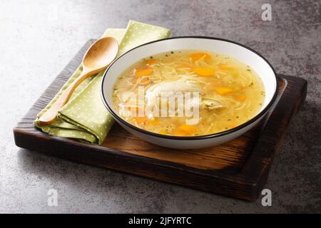 Délicieux bouillon de poulet maison avec nouilles et légumes dans une assiette sur un plateau en bois horizontal Banque D'Images