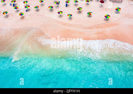 Parasols multicolores sur la plage tropicale lavée par les vagues de la mer des Caraïbes, vue aérienne, Antigua, Antilles, Caraïbes, Amérique centrale Banque D'Images