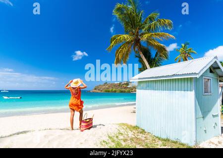 Belle femme avec chapeau de paille et robe de détente sur la plage tropicale, Antigua, îles Leeward, Antilles, Caraïbes, Amérique centrale Banque D'Images