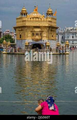 Amritsar ,8 ,avril :2014,réflexion du complexe du Temple d'Or avec des dévotés dans l'étang Saint, Amritsar, Punjab, Inde Banque D'Images