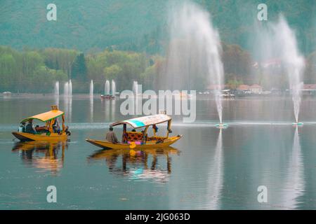 Srinagar, 10, avril 2016; réflexion d'un petit bateau avec la famille Kashmiri en costume traditionnel traversant le lac Dal, Srinagar, Cachemire, Inde Banque D'Images