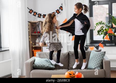 les filles en costumes d'halloween sautant sur le canapé Banque D'Images