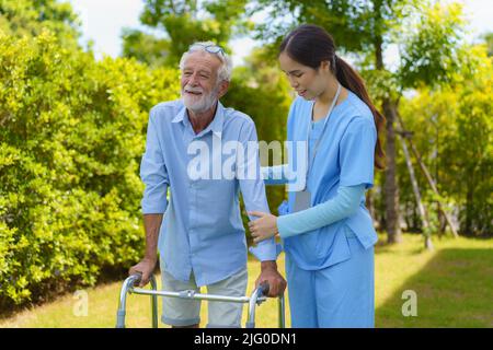 Jeune femme asiatique infirmière soignant aidant le vieil homme âgé avec mobilité marcheur dans le jardin à la maison. Centre de garderie, infirmière prend soin des patients âgés Banque D'Images