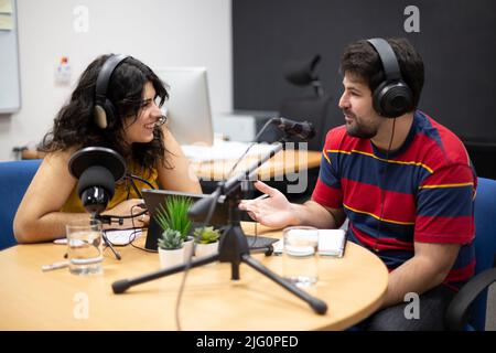 Homme interviewant une femme invitée pendant l'enregistrement en direct d'un podcast ou d'une émission de radio. Concept de communication en ligne et de création de contenu. Banque D'Images