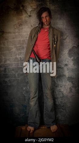 Junkie homme avec cheveux noirs et bouteille avec joint près de vieux mur de pierre Banque D'Images