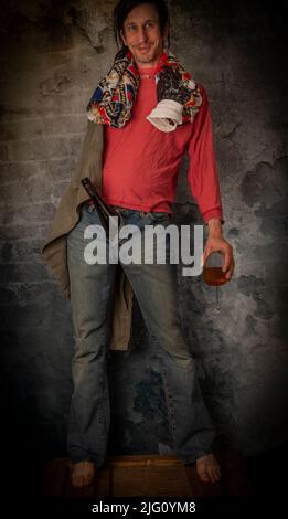 Junkie homme avec cheveux noirs et bouteille avec joint près de vieux mur de pierre Banque D'Images