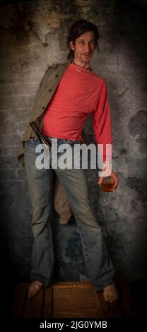 Junkie homme avec cheveux noirs et bouteille avec joint près de vieux mur de pierre Banque D'Images