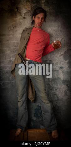 Junkie homme avec cheveux noirs et bouteille avec joint près de vieux mur de pierre Banque D'Images