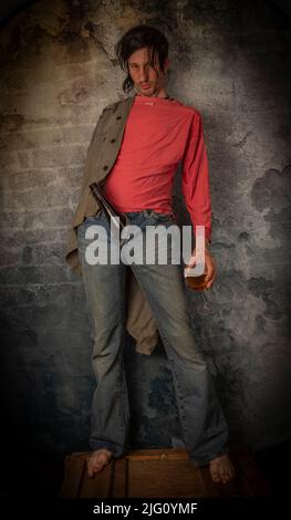 Junkie homme avec cheveux noirs et bouteille avec joint près de vieux mur de pierre Banque D'Images