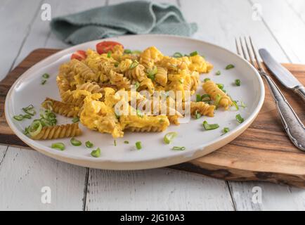 Remuez les nouilles de blé entier frites avec des œufs brouillés sur une assiette. Repas sain et bon marché Banque D'Images