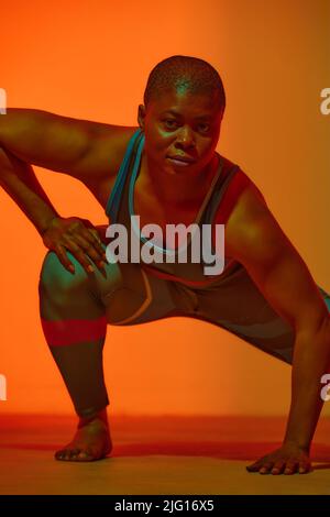 Portrait d'une jeune femme noire heureuse en tenue de sport posant et souriant sur fond jaune de studio. S'adapte à la femme afro-américaine du millénaire Banque D'Images