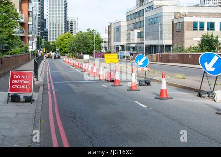 Travaille sur un pont réduisant deux voies à une voie avec des cônes rouges Banque D'Images