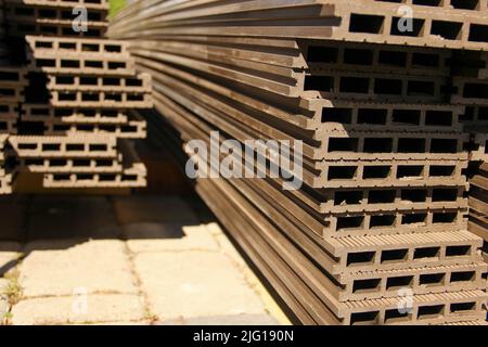 Vue en profil des planches de terrasse composites mises dans un tas. Terrasse en composite bois-plastique. Banque D'Images