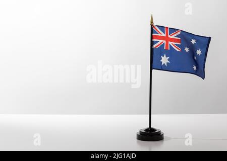 Pays volant drapeau Australie isolé sur une table blanche avec un fond gris Banque D'Images