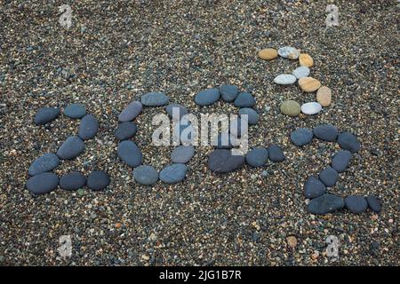 Retournement de 2022 à 2023 fait de pierres sur la plage. Préparation changement de nouvelle année Banque D'Images
