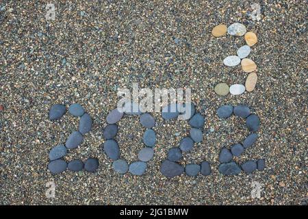 Retournement de 2022 à 2023 fait de pierres sur la plage. Préparation changement de nouvelle année Banque D'Images