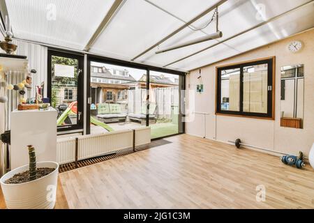 Cette chambre spacieuse et lumineuse dispose de parquet, d''un radiateur, d''haltères, d''une barbell et de fenêtres et d''une porte donnant sur la cour Banque D'Images