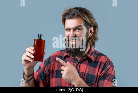 L'homme tient une bouteille de shampooing ou de gel douche. Après-shampooing pour hommes. Soin expert pour les cheveux exigeants. Contenant en plastique avec shampooing. Jeune beau Banque D'Images