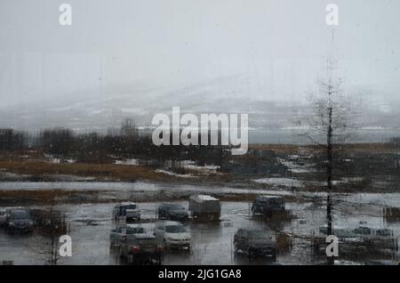 Verre dans un bâtiment couvert de gouttes de pluie, vue sur un parking pluvieux par la fenêtre. Banque D'Images