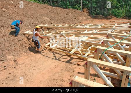 L'équipe de travail construction maison en bois stick built house accueil mesure de coupe à clouer sur journée chaude Banque D'Images