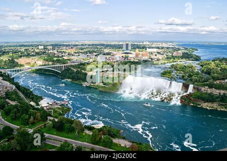 Vue panoramique des chutes du Niagara dans la journée sur la rivière avec rochers et bateau. Banque D'Images