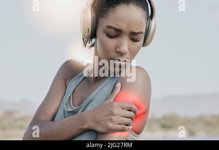 Athlète féminine avec une douleur d'épaule après un entraînement intense. Jeune femme sportive blessée ou blessée au bras mise en évidence en rouge. Une femme sportive Banque D'Images