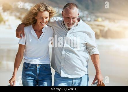 Couple d'âge mûr souriant s'embrassant et marchant pendant des vacances à la plage outre-mer. Mari et femme heureux profitant de temps libre et de vacances. Homme et femme Banque D'Images