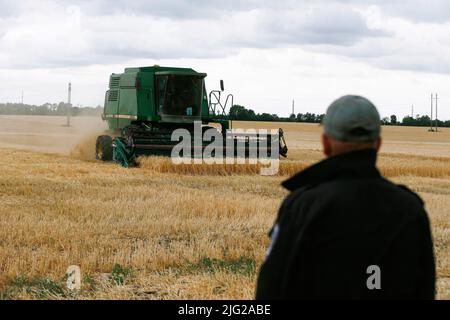 Odessa, Ukraine. 23rd juin 2022. Un agriculteur considère qu'une moissonneuse-batteuse récolte des céréales d'orge dans un champ de la région d'Odesa, dans le sud de l'Ukraine. Alors que l'invasion russe se poursuit en Ukraine, plus de 20 millions de tonnes de céréales ukrainiennes ont été bloquées dans les ports ukrainiens, dont une part importante était destinée au Programme alimentaire mondial de l'ONU, selon les médias locaux. (Photo de Pavlo Gonchar/SOPA Images/Sipa USA) crédit: SIPA USA/Alay Live News Banque D'Images